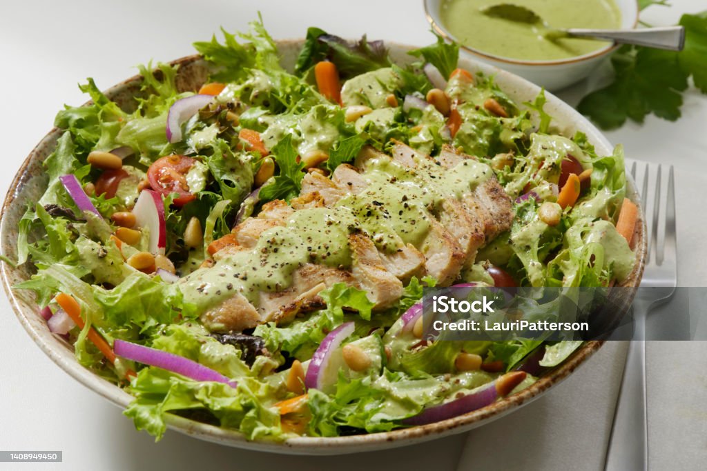 The Viral Green Goddess Salad with Grilled Chicken and  Mixed Greens The Viral Green Goddess Salad with Grilled Chicken. Mixed Greens, Radish, Carrots, Tomatoes, Onions, Cucumbers andd Toasted Pine Nuts with a Creamy Cilantro and Avocado Dressing Salad Bowl Stock Photo