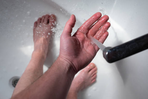 Cold water flows from the faucet. a man is trying to take a cold shower. stock photo