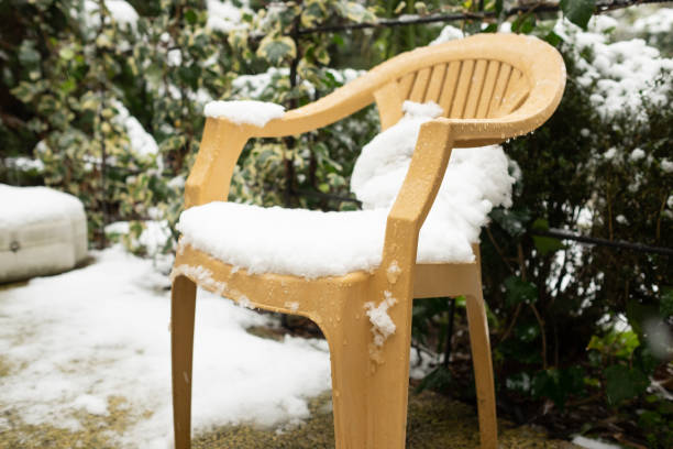 istock snow on plastic chair in small yard. Unexpected frosts in spring 1408950819