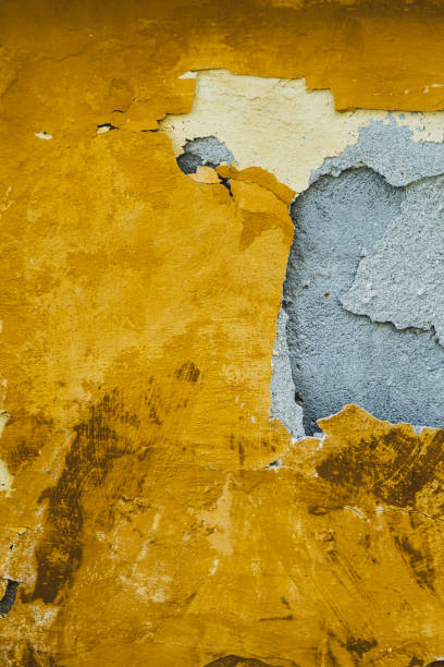 istock Yellow paint peeling off cement wall. 1408952358
