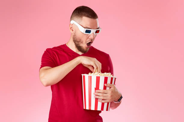 istock Young caucasian man in 3d glasses eating popcorn 1408953936