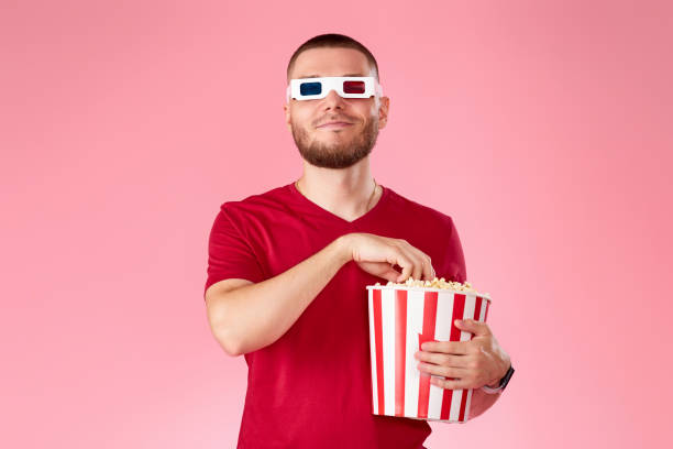 istock Young caucasian man in 3d glasses eating popcorn 1408953937