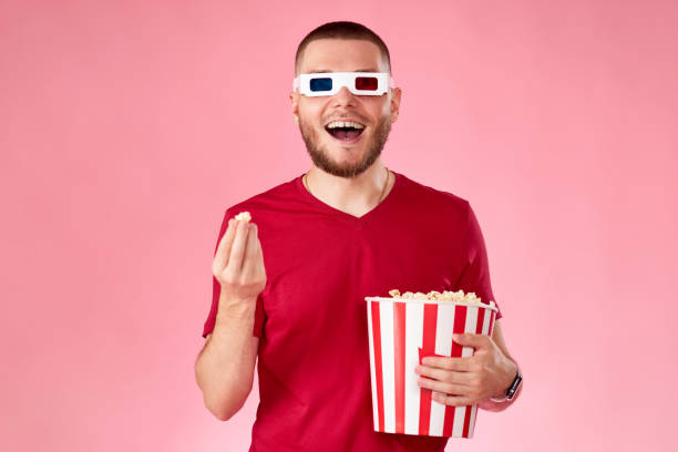 istock Young caucasian man in 3d glasses eating popcorn 1408953940