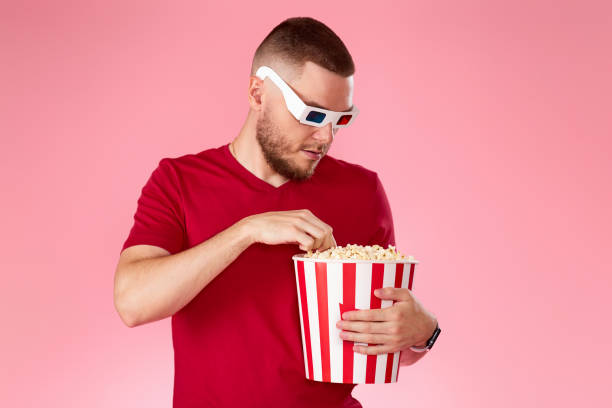 istock Young caucasian man in 3d glasses eating popcorn 1408953953