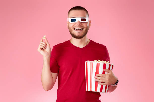 istock Young caucasian man in 3d glasses eating popcorn 1408953955