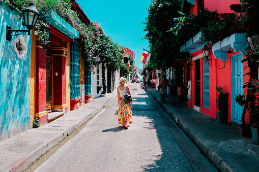 Young woman walking on a colorful street in old city of Cartagena, Colombia