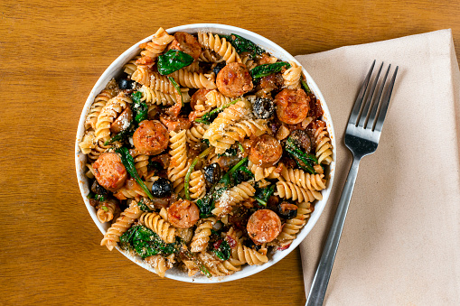 rotini pasta served with italian sausage and sauteed spinach.