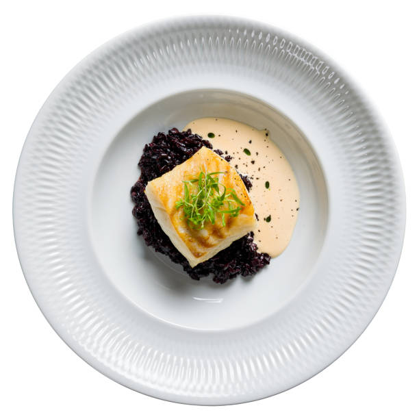 czarne risotto ze smażonym halibutem na białym talerzu izolowanym na białym tle widok z góry - płastuga zdjęcia i obrazy z banku zdjęć