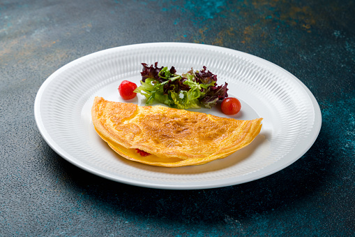 omelette breakfast on a white plate with tomatoes