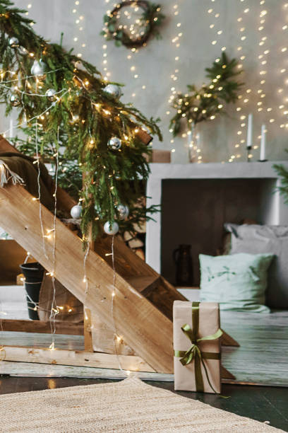 tver, russia-november 10, 2021. home new year's interior. a live christmas tree and a wooden staircase in the kitchen. cozy atmosphere of a home holiday, loft design of the room, daylight, green christmas tree decorated with lights - christmas tree stockfoto's en -beelden