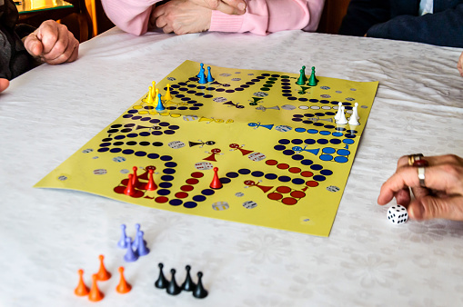 In a social center, a group of active seniors are enjoying playing ludo game.