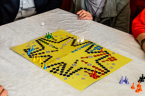Playing with ludo game with a small group of active seniors makes a social gathering fun.