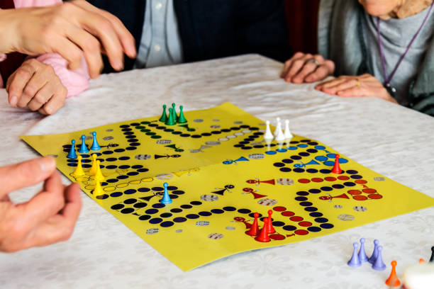 los participantes mayores en una reunión social se divierten mucho jugando al juego de ludo. - traditional games fotografías e imágenes de stock