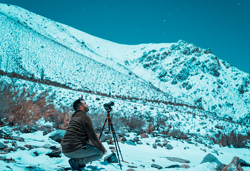 young latin photographer in the snow at night taking pictures of the stars, valle del Elqui, Chile