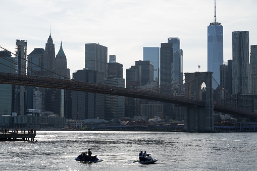 New York, NY, USA - June 6, 2022: Jet skis on the East River against the backdrop of the Lower Manhattan skyline and Brooklyn Bridge.