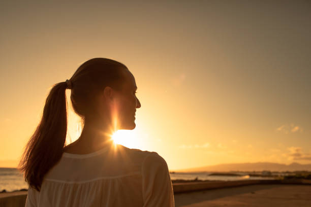 istock Woman enjoying beautiful sunset at the beach. 1408975552
