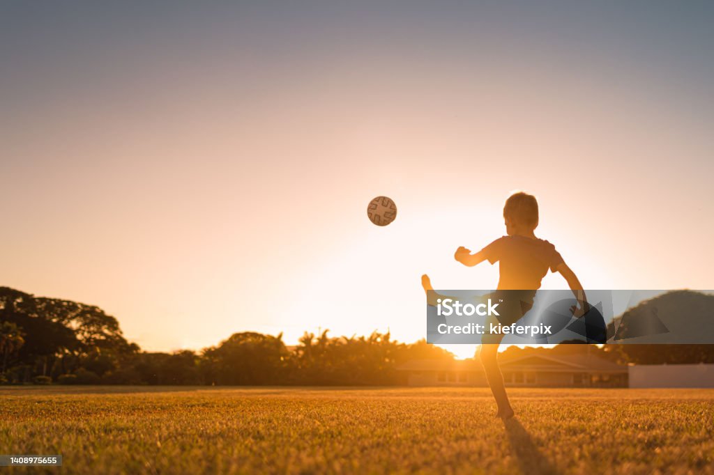 Boy playing soccer at sunset. Boy playing with a ball during sunset outdoors. Child Stock Photo