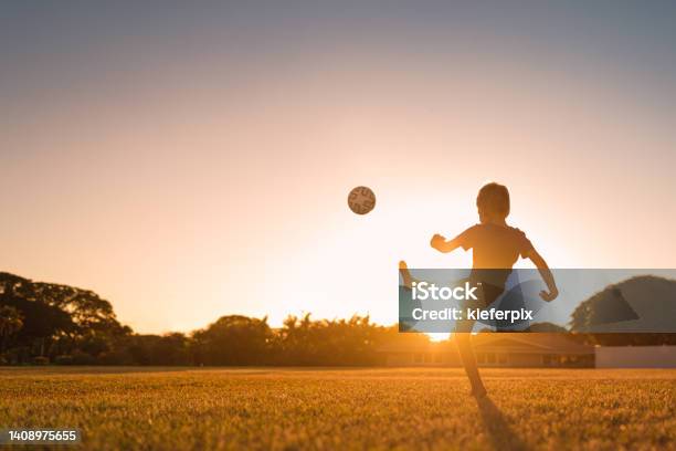 Boy Playing Soccer At Sunset Stock Photo - Download Image Now - Child, Soccer, Playful