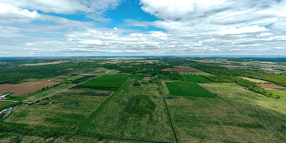 A very wide aerial view of farmland and rural wisconsin in spring under a cloudy blue sky