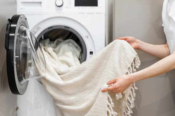 Woman unloading laundry from white washing machine stock photo