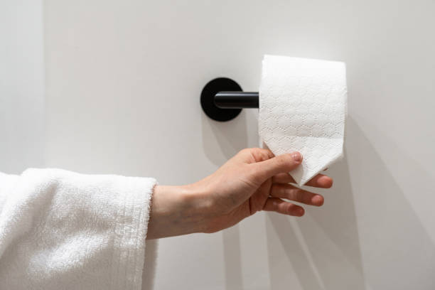 Woman hand take piece of toilet paper Cropped view of woman hand take piece of toilet paper with folded corner. Woman hold roll of soft hygienic tissue. Hygienic concepts in hotel, home and public restrooms toilet paper stock pictures, royalty-free photos & images