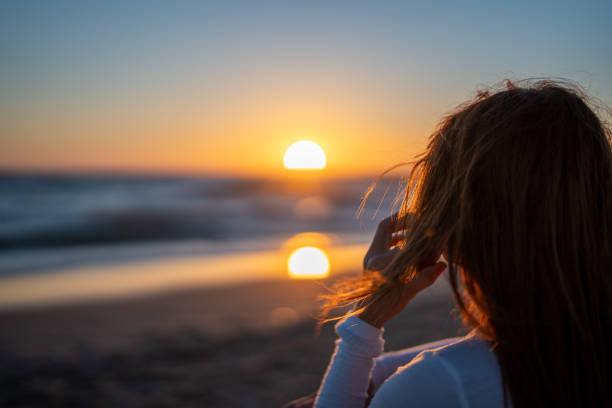 istock red-haired woman talking on her cell phone while watching the sunset over the ocean 1408982246