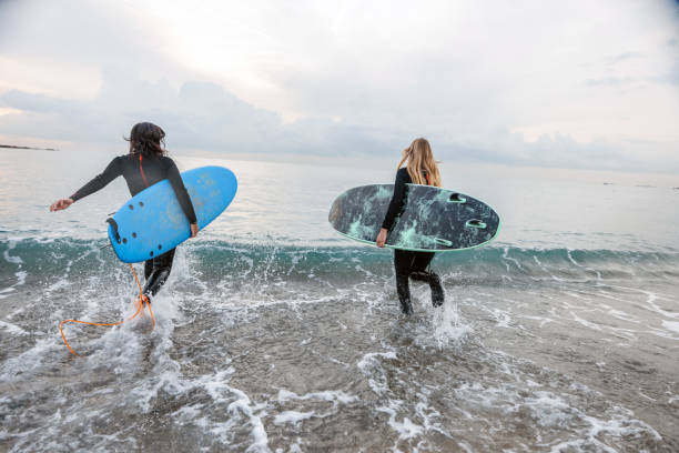 istock Female Surfers With Boards Running Into Water 1408982831