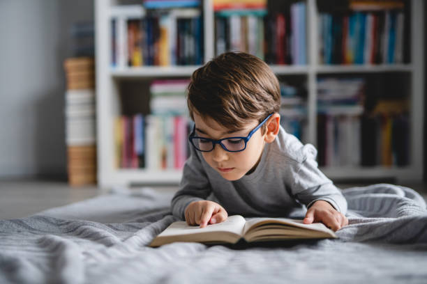 istock One caucasian boy lying on the floor at home in day reading a book front view wearing eyeglasses copy space real people 1408986143