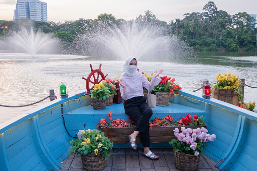Jakarta, Indonesia - February 12,2022: Visiting Senayan Park, women take pictures and sit on miniature ships and near fountains.