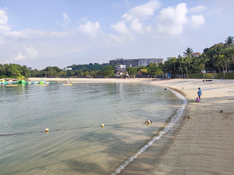 Singapore- Apr 2, 2022: Shore and beach at Sentosa island in Singapore. It is an artificial beach with a sand taken from Malaysia and Indonesia.