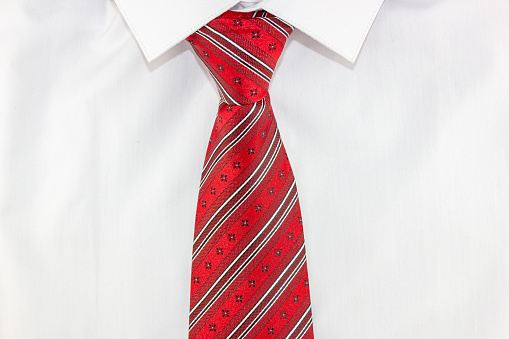 The Men's white shirt with a red tie close-up. Business image style scarlet tie and white shirt.