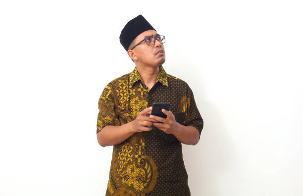 istock Thoughtful face of Asian man while holding at his cellular phone. Isolated on white background 1409003285