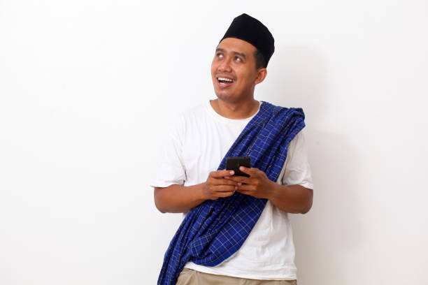 istock Happy asian man while standing, holding a cellular phone and looking at blank space. Isolated on white background 1409010847