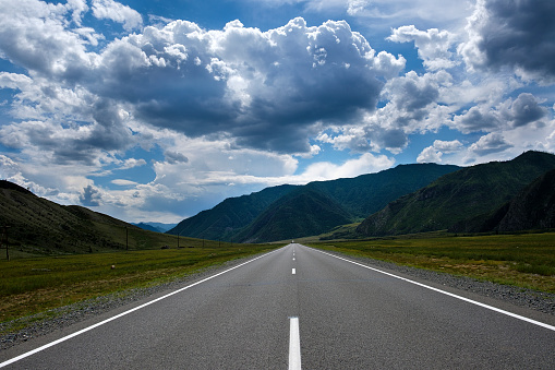 the ribbon of the road among the slopes of the mountains on the expanses of Altai on a summer day