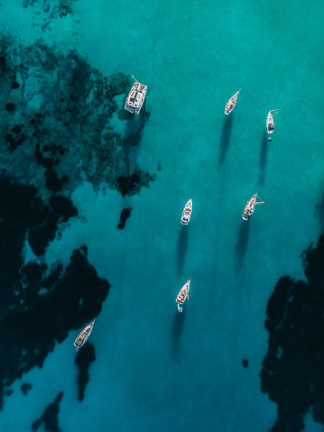 Aerial drone photos of sailboats and yachts in  secluded beaches and turquoise ocean in the  mediterranean sea of Ibiza, Spain