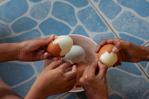 Hands of the children help peeling eggs happily.