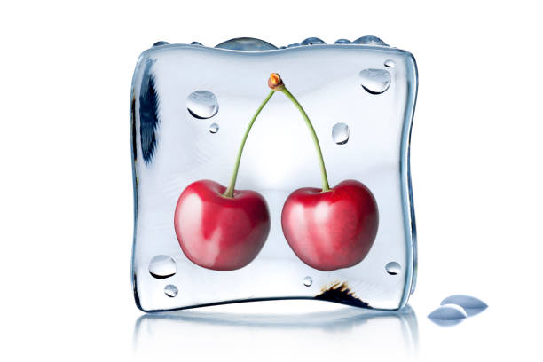 A cherry dropped into a bowl of water with some other berries