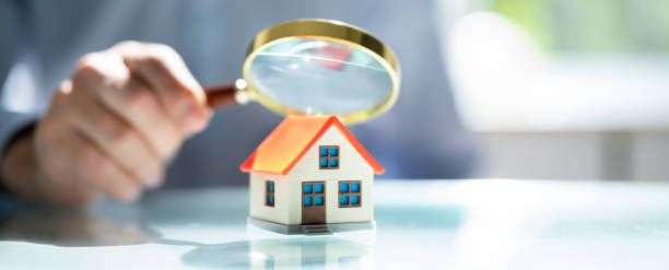 istock Businessman Holding Magnifying Glass Over House Model 1409041143