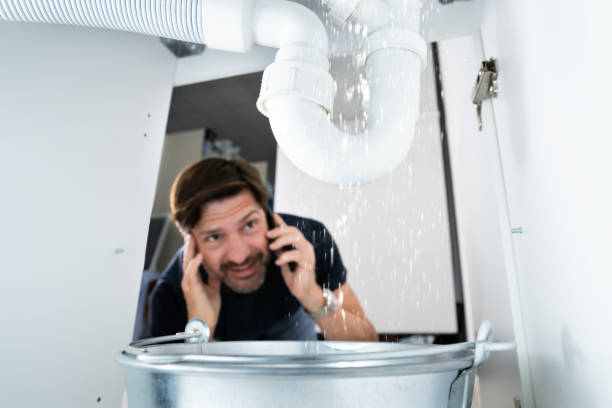 Worried Man Calling Plumber Worried Man Calling Plumber While Watching Water Leaking From Sink leaking stock pictures, royalty-free photos & images
