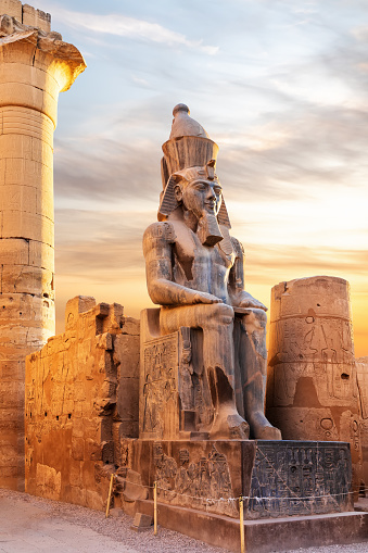 Seated statue of Ramesses II by the Luxor Temple entrance, sunset scenery, Egypt.