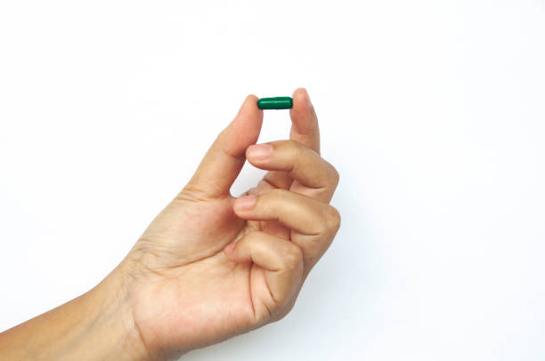 istock Female hand picking one pill isolated on white background. 1409045029