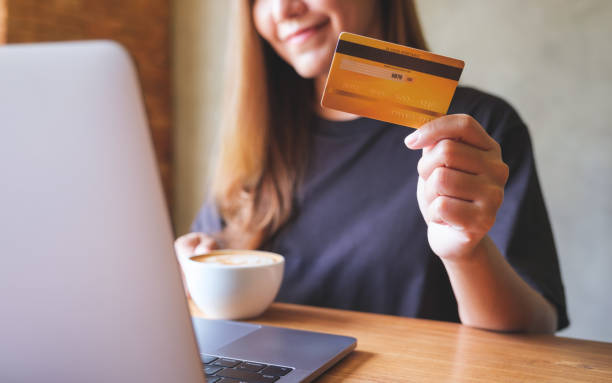 istock Closeup image of a woman holding coffee cup and credit cards while using laptop computer for online payment 1409045437