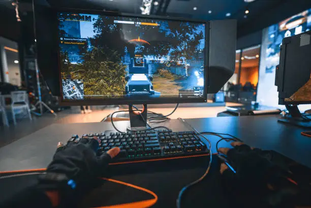 Photo of first person view asian esports team player playing shooting game with his teammates in grand final esport arena with live broadcasting against other team