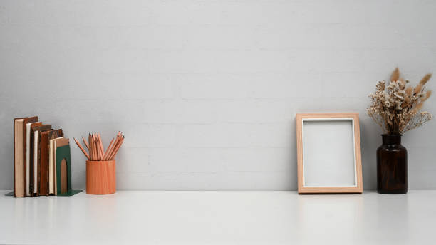 istock Home office desk with blank picture frame, books and stationery. Copy space for text. 1409048340