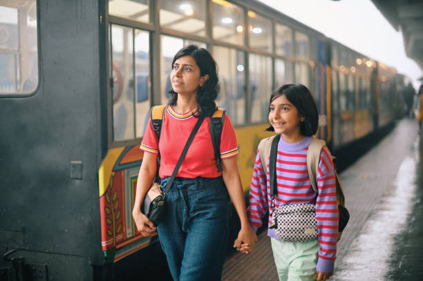 istock Mother and daughter walking at a train station platform while a train is halted at the platform 1409049759