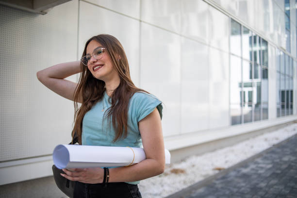 Portrait of a female student in casual clothes, she is standing in front of the faculty building
