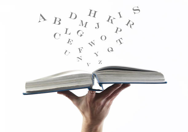 libro aperto con lettere volanti sparse su sfondo bianco. concetto di educazione. - dictionary alphabet letter text foto e immagini stock