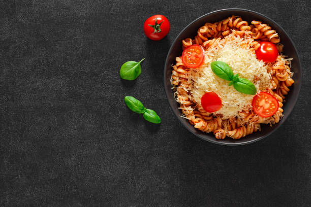 istock Fusilli, cooked pasta with tomato sauce, basil, grated parmesan and cherry tomatoes, top view, space to copy text. 1409062611