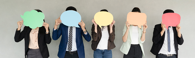 Panoramic banner image of Business Team Holding Speech Bubble icon over gray background.wide crop