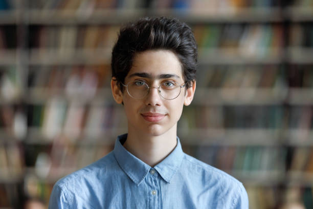 Head shot portrait student guy in glasses posing in library Head shot schoolboy guy posing in campus library on bookshelves background. 17s pupil in eyeglasses look at cam. Excellent student portrait, skill and knowledge, education, generation Z person concept judaism photos stock pictures, royalty-free photos & images